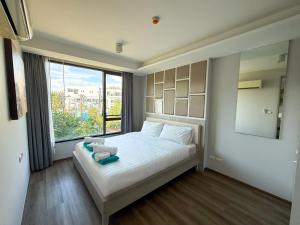 ein Schlafzimmer mit einem weißen Bett mit einem großen Fenster in der Unterkunft 6th Avenue 2 bedroom in Surin Beach