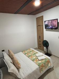 Apartamento Jardines Guaduas Cundinamarca في غوادواس: غرفة نوم مع سرير وتلفزيون على الحائط