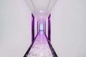 an empty corridor in a white building with purple floors at HOTEL O HAPPY PLACE HOTEL & RESORT in Gaya