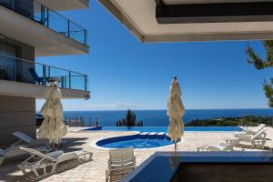 uitzicht op een zwembad met stoelen en parasols bij Skyline View Apt & Pool Retreat in Budva