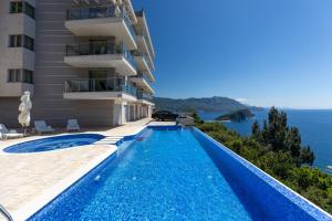 een zwembad voor een gebouw met uitzicht op de oceaan bij Skyline View Apt & Pool Retreat in Budva