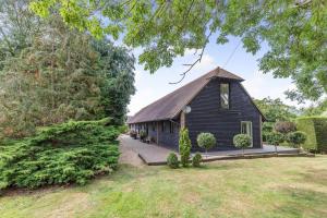 a small black house with a thatched roof at Frith Farm House Cottages in Newnham