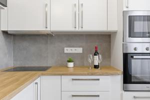 una cucina con armadi bianchi e bicchieri da vino su un bancone di Apartmán Géčko a Boží Dar