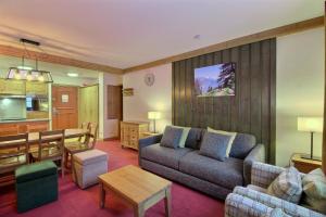 un salon avec un canapé et une table dans l'établissement ARC 1950 - Appartement 6 personnes - Départ ski aux pieds - Sauna, Hammam, Jacuzzi, Piscine chauffée, à Arc 1950