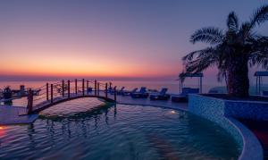 Litz Resort في كفارياتي: حمام سباحة مع جسر وغروب الشمس
