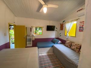 a living room with a couch and a ceiling fan at Tia Chica Camburi in Camburi