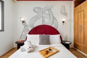 The Loft Residence by GoodMove - Maarif Casablanca في الدار البيضاء: سرير ذو لوح أمامي أحمر مع صينية طعام عليه +97 صورة