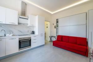 un sofá rojo en una cocina con armarios blancos en Harmony's Nest - Vicino a treno e Fiera Milano, en Rho