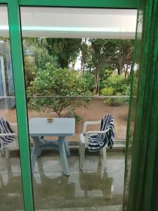 ein Glasfenster mit einem Tisch und 2 Stühlen in der Unterkunft Dar Sabrina Bizerte Corniche in Banzart