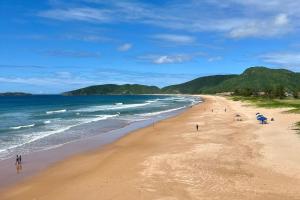 Una playa con gente caminando sobre la arena y el océano. en Estúdios Sol e Mar, aconchego e charme em Tucuns, en Búzios