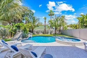 a swimming pool with chairs and palm trees at Gulfside Green Estate in Siesta Key +59 photos