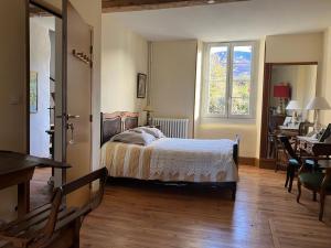 a bedroom with a bed and a desk and a window at Le verger d'Aglaé&Michel in Verdun