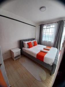 a bedroom with a bed with orange pillows and a window at Delightfulstaycation in Nanyuki +3 photos