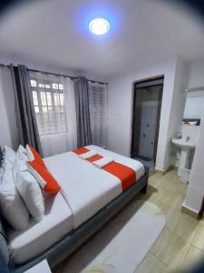 a bedroom with a bed with orange and white pillows at Delightfulstaycation in Nanyuki