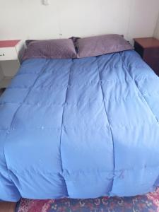 eine blaue Bettdecke auf einem Bett in einem Zimmer in der Unterkunft Casa silvia in Llanquihue