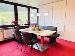 Serenity Stay Baiersbronn Kamin und Schwarzwaldblick في بايرسبرون: غرفة طعام مع طاولة وبعض الكراسي