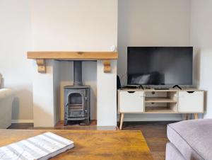 Pickleberry Cottage - Close to sandy beach في ويست ويتيرينغ: غرفة معيشة مع مدفأة وتلفزيون