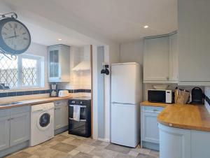 Pickleberry Cottage - Close to sandy beach في ويست ويتيرينغ: مطبخ مع ثلاجة وساعة على الحائط
