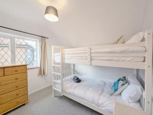 Pickleberry Cottage - Close to sandy beach في ويست ويتيرينغ: غرفة نوم مع سريرين بطابقين وخزانة
