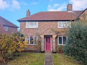 Pickleberry Cottage - Close to sandy beach في ويست ويتيرينغ: منزل من الطوب الأحمر مع باب احمر