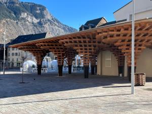 a wooden pavilion in front of a building with a mountain at Guimbert'Home in Le Bourg-dʼOisans