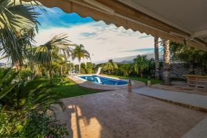 an outdoor patio with a swimming pool and palm trees at Casa Rural EL CAMPICO in Puerto de Mazarrón