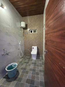 a small bathroom with a toilet and a door at Ananya home stay hampi in Hampi
