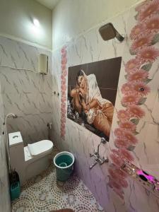 a bathroom with a toilet and a painting on the wall at Ananya home stay hampi in Hampi