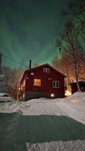 Un granero rojo en la nieve por la noche en Fox Cabin, en Lyngen