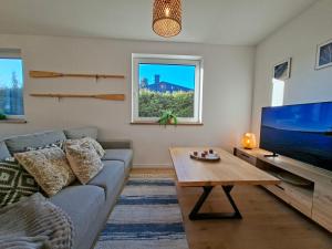 Una sala de estar con un sofá y un televisor grande. en Lake House Szteklin, en Szteklin