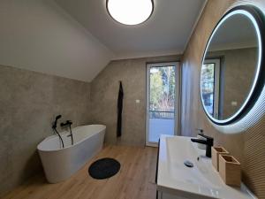 Un baño con bañera y un espejo grande. en Lake House Szteklin, en Szteklin 40 fotos más