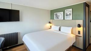 a bedroom with a large white bed and a flat screen tv at Campanile NATURE - Vierzon in Vierzon +21 photos