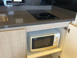 South pattaya Unixx hotel في جنوب باتايا: فرن مايكرويف تحت كونتر في مطبخ