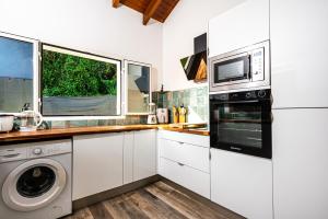 a kitchen with a washer and dryer and a microwave at La Kaz Zen - Cozy house with garden in Les Abymes +6 photos