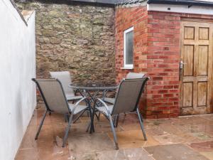 a table and four chairs in front of a brick wall at Levenside in Garstang