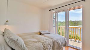 a bedroom with a bed and a balcony with a window at Hideaway in Herolds Bay
