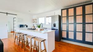 a kitchen with a white counter and wooden stools at Hideaway in Herolds Bay