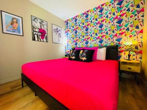 a bedroom with a large red bed with a colorful wall at Radical 80's Getaway! A Blast From The Past! in Sandusky