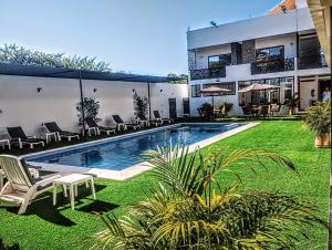 a house with a swimming pool with chairs and grass at Houzze Plety in Brisas de Zicatela