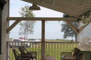 a screened porch with chairs and a view of a field at Fundy Footprints in Saint Martins