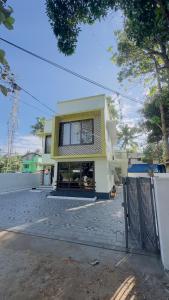 a yellow and white house with a fence in front of it at TAMARA VISTA Executive Homestay in Varkala
