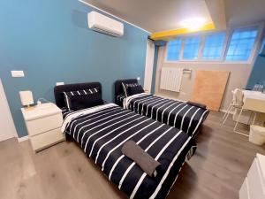 two beds in a room with blue walls at B&B Pizza Room Twin Room near Navigli Milan in Milan