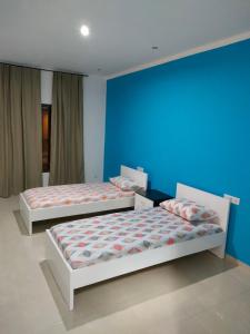 two beds in a room with a blue wall at Residencial oliveira in Porto Novo