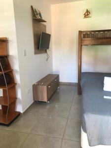 a bedroom with a bed and a tv on a wall at Apart Hotel Guaiuba in Guarujá