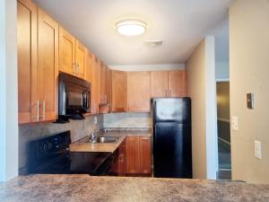 a kitchen with wooden cabinets and a black refrigerator at Long term 1BR w Balcony & Parking Near Philly in Jenkintown