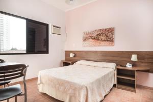 a bedroom with a bed and a table and a desk at Hotel Marmo in Jacareí +20 photos
