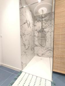 een douche in een kamer met een marmeren muur bij L'Océan - Ambiance Apaisante & Rafraichissante in Biville-sur-Mer +21 foto's