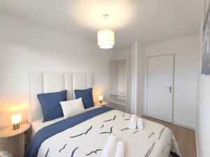 een slaapkamer met een groot bed met blauwe kussens bij L'Océan - Ambiance Apaisante & Rafraichissante in Biville-sur-Mer