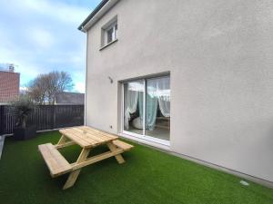 een picknicktafel en een bankje aan de zijkant van een huis bij L'Océan - Ambiance Apaisante & Rafraichissante in Biville-sur-Mer