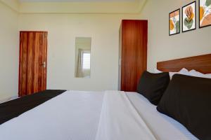 MuthugadahalliにあるHotel O Airport Nestの木製のヘッドボードが付いた白いベッドのある寝室